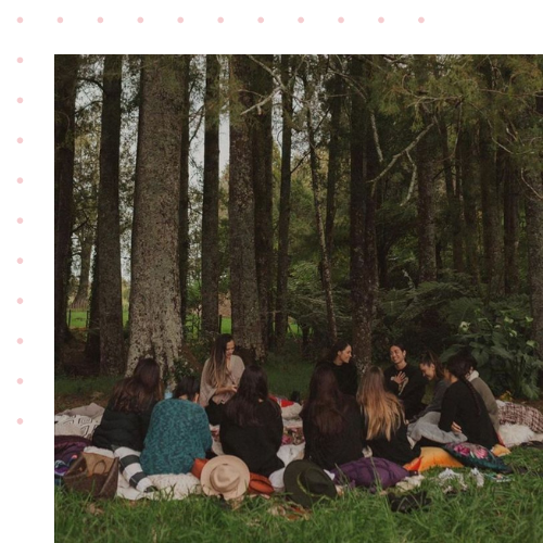 A group of people sitting around in a circle having an outdoor picnic