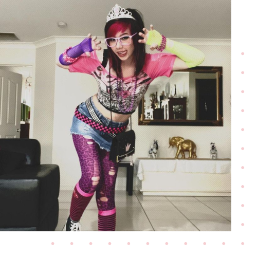 A girl standing in a living room wearing extremely colorful clothes and accessories